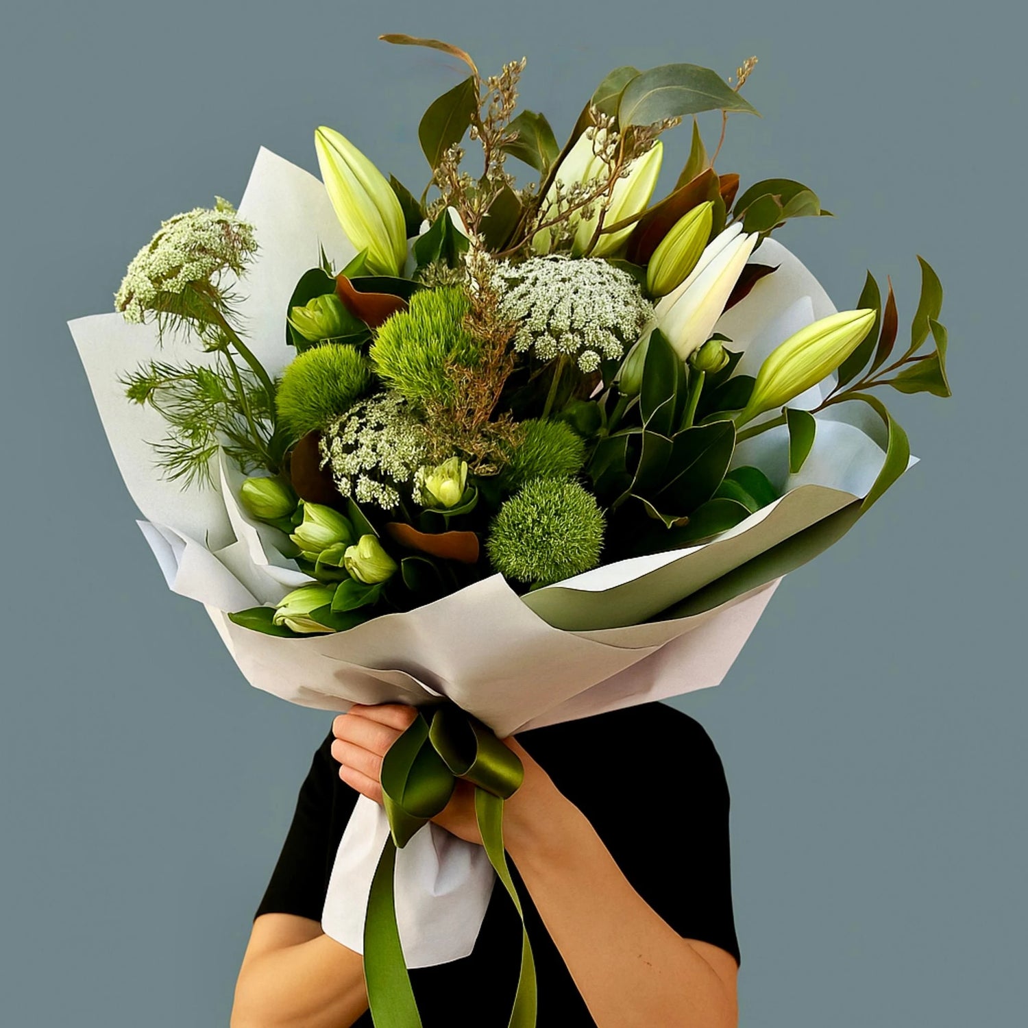 A woman earing black, holding a bouquet of Australian native wildflowers  in a bouquet.