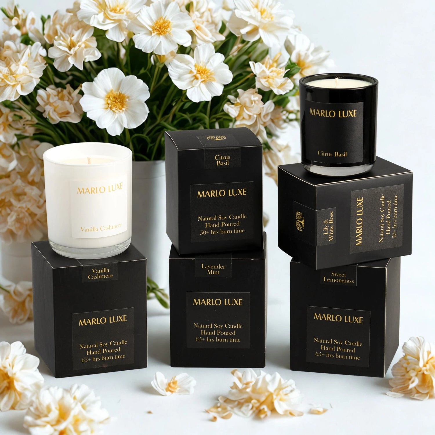 A selection of candles in white glass and packaged in a black bow with gold font.