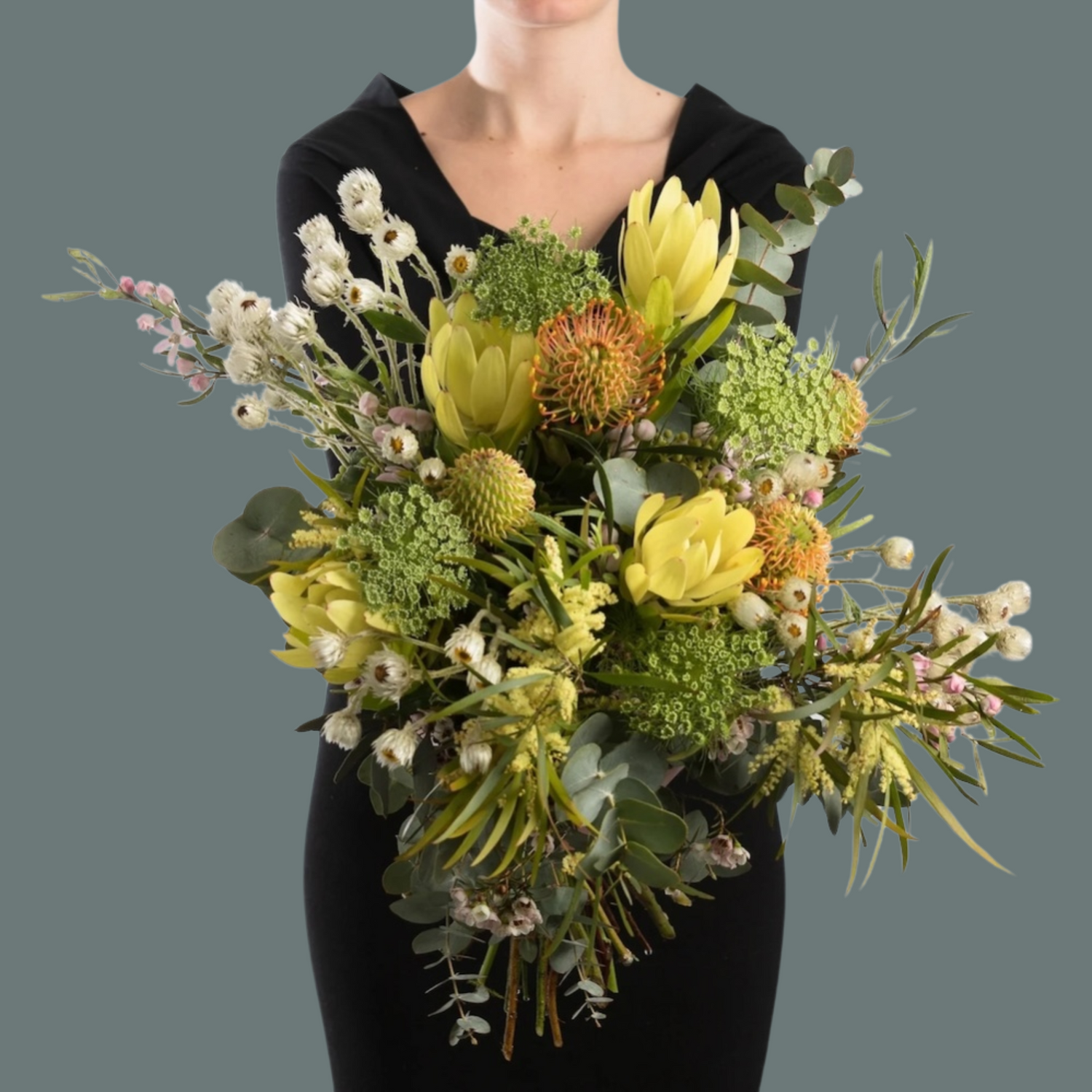 A woman earing black, holding a bouquet of Australian native wildflowers  in a bouquet.